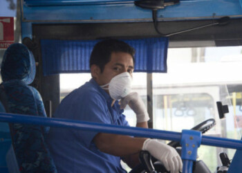 A bus driver wears a protective mask as a preventive measure against the spread of the COVID-19 Coronavirus, at a transfer station in Quito, on March 13, 2020. (Photo by Rodrigo BUENDIA / AFP)