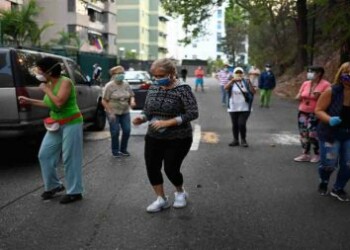 People dance during a concert offered by Venezuelan singer Yvanno Pichardo in the street in Colinas de Bello Monte neighbourhood in Caracas to liven up the COVID-19 coronavirus lockdown, on April 24, 2020. - Besides from clapping to pay tribute to medical teams fighting COVID-19, people around the globe are also getting out to their balconies and windows to share some lockdown-time with music. (Photo by Federico PARRA / AFP)