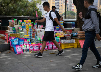 AME7281. CARACAS (VENEZUELA), 30/03/2023.- Personas caminan frente a puesto informal de comida y productos básicos, el 23 de marzo de 2023 en Caracas (Venezuela). El salario mínimo en Venezuela, que ha aumentado desde hace un año de 7 bolívares (1,60 dólares) a 130 bolívares (29,68 dólares), se ha reducido desde entonces un 82 % en su equivalente en la divisa estadounidense -referencia en el país para fijar precios- hasta 5,31 dólares, como consecuencia de la devaluación de la moneda local. EFE/ Rayner Peña R