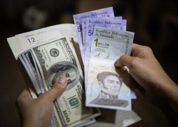 AME9701. CARACAS (VENEZUELA), 02/07/2021.- Una persona sostiene un fajo de billetes de dolar y bolívares el 01 de julio de 2021, en Caracas (Venezuela). Venezuela lleva inmersa en la pesadilla de la hiperinflación desde noviembre de 2017, una época de cifras mareantes que ha derivado en una dolarización espontánea como boya de salvación. Sin embargo, en los últimos meses, el incremento de los precios ha comenzado a frenarse, lo que alimenta la esperanza de dejar atrás el mal sueño. EFE/ Rayner Peña R