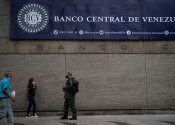 People walk in front of the main facade of the Central Bank of Venezuela in Caracas on August 25, 2022. (Photo by Yuri CORTEZ / AFP)
