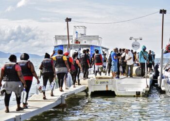 Stranded migrants, mostly from Venezuela, get on a boat in the Colombian port town of Necocli, to cross into neighbouring Panama to continue their journey towards the United States, on October 11, 2022. - Thousands of US-bound migrants, mostly from Venezuela, remain stranded in Necocli as they wait for boats to cross them into neighbouring Panama to continue they dangerous journey north. (Photo by Danilo GOMEZ / AFP)