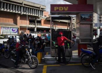 Motorcyclists queue to fill the tank of their bikes in a gas station in Caracas on October 5, 2020, amid the new coronavirus pandemic. - Venezuela launched this Monday a plan to distribute gasoline according to the registration numbers of the vehicles, a measure in response to the severe fuel shortage in the Caribbean country. (Photo by Cristian Hernandez / AFP)